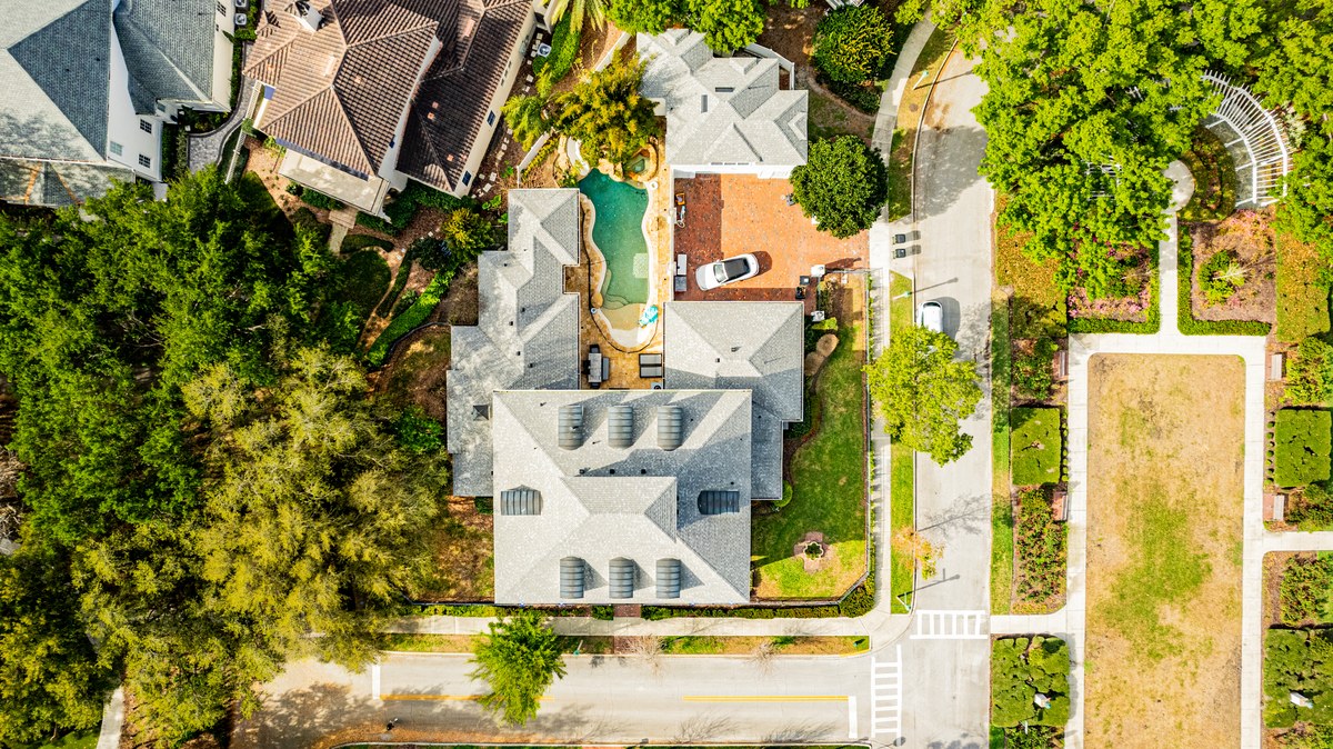 Top-down aerial of a large home with a screened pool among mature trees in Celebration