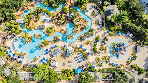 Top-down aerial of a resort water park with a lazy river and blue umbrellas in Champions Gate