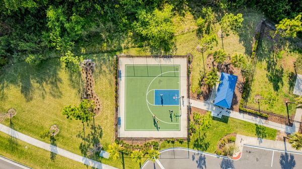 Top-down aerial of a fenced sports court surrounded by trees in Odessa