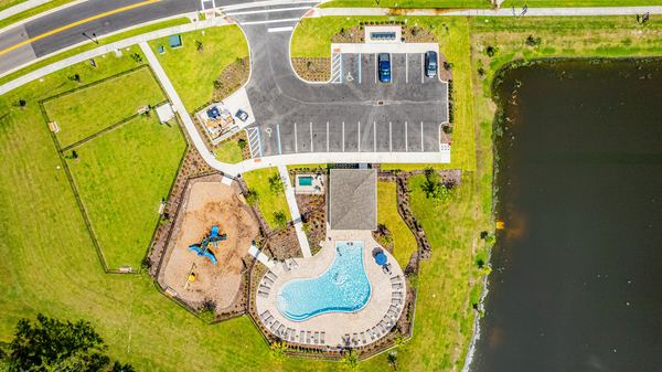 Aerial of a clubhouse with pool and playground beside a pond in Poinciana
