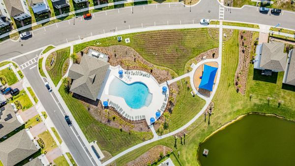 Aerial of a community pool beside a pond and street in St. Cloud