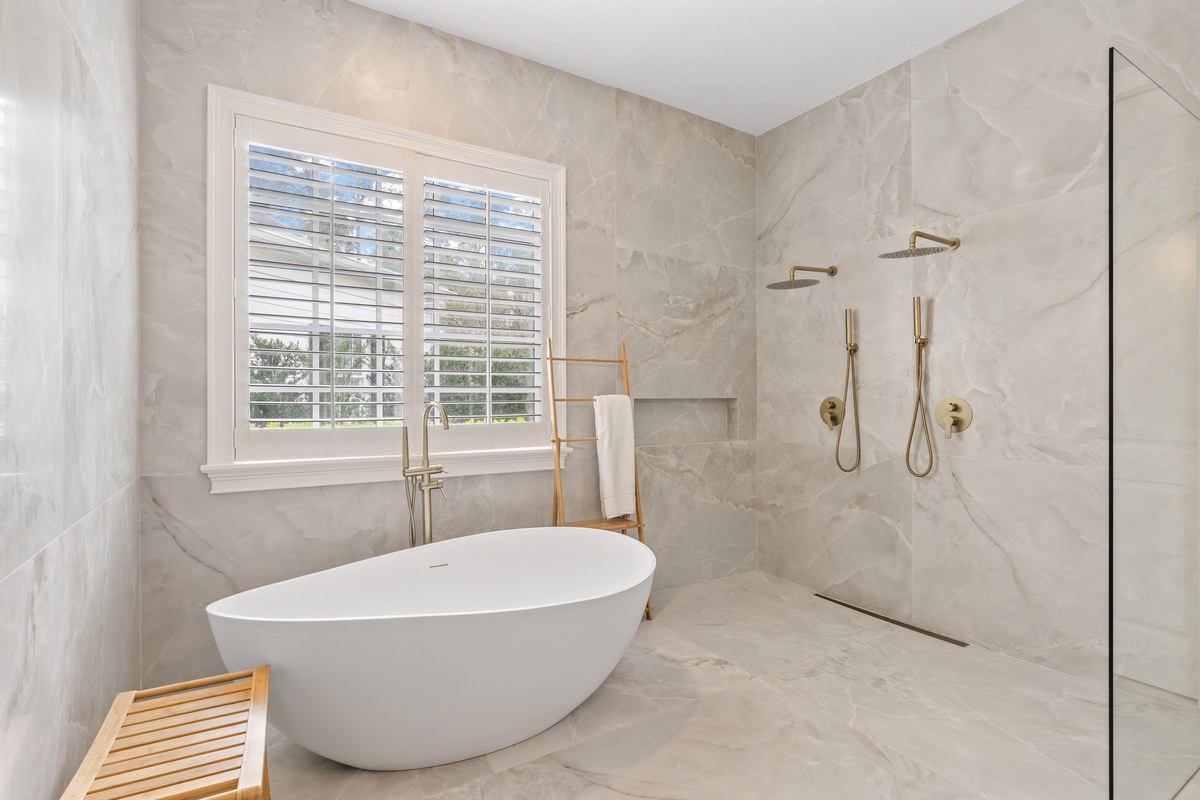 Bathroom with a freestanding tub and marble-look walls in Celebration