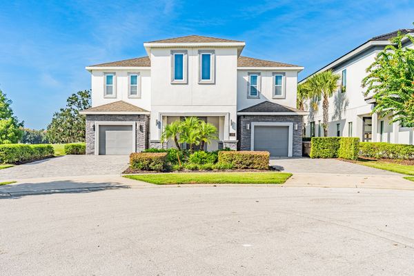White stucco two-story home with two garage bays and a tile roof in Champions Gate