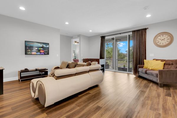 Living room with a long sofa, sliding doors and a television on screen in Champions Gate
