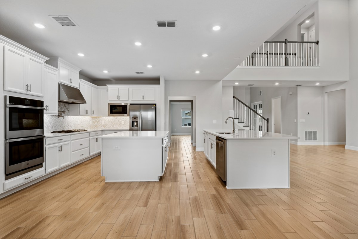 White kitchen open to a stair hall with wood floors in Clermont