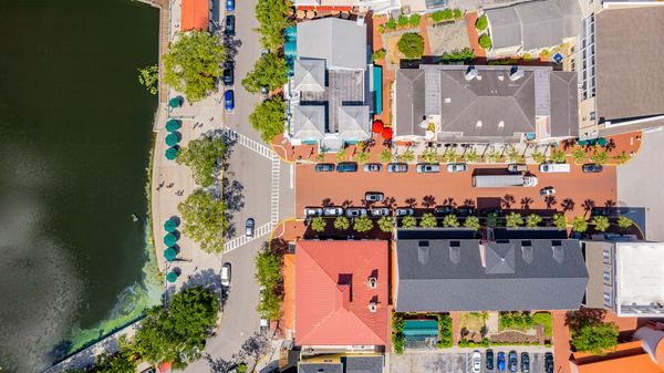 Aerial of a lakefront downtown block with tile and metal roofs and angled parking in Celebration