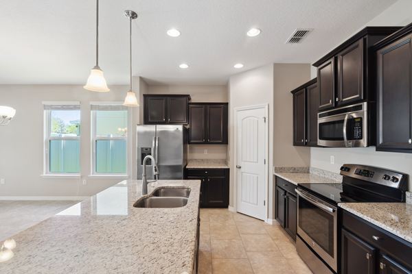 Kitchen with dark cabinets, a granite island and pendant lights in Eustis