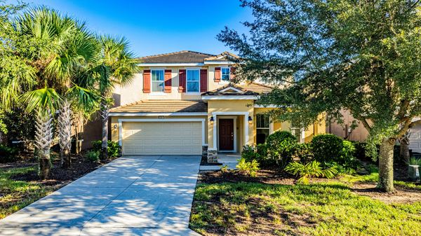 Elevated view of a tan home with palms and a paver driveway in Four Corners
