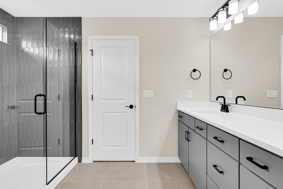 Bathroom with a dark tile shower and a gray vanity in Hamlin