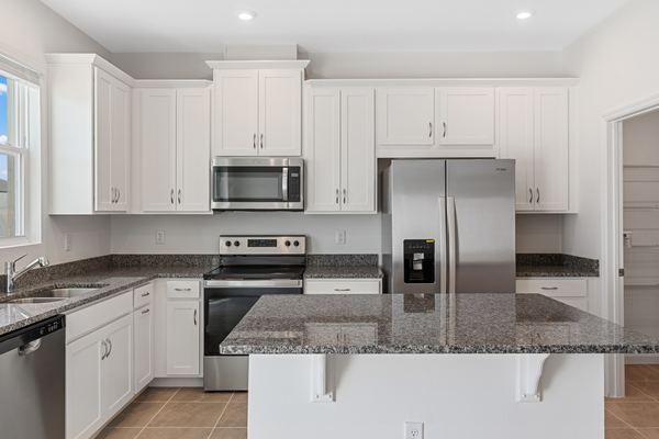 Kitchen with white shaker cabinets, speckled granite counters, a granite-topped island and a full stainless appliance set.