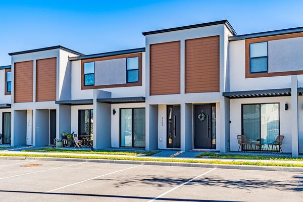 Modern brown and white townhome row with patio tables at each door in Kissimmee