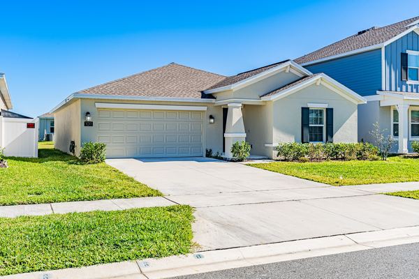 Cream single-story home with an attached garage on a corner lot in Kissimmee