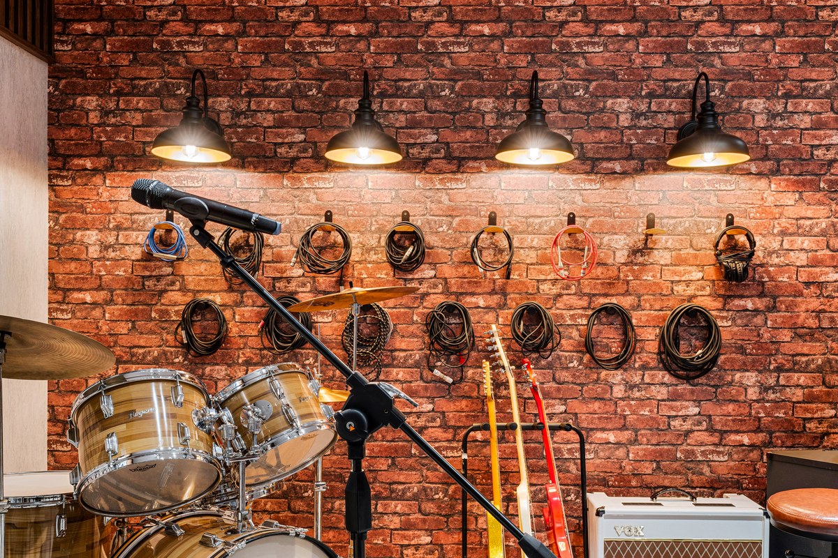 Drum kit and guitars on a brick wall under industrial lights in Kissimmee