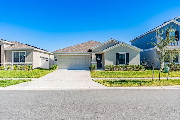 Single-story home with a two-car garage under a clear sky in Kissimmee
