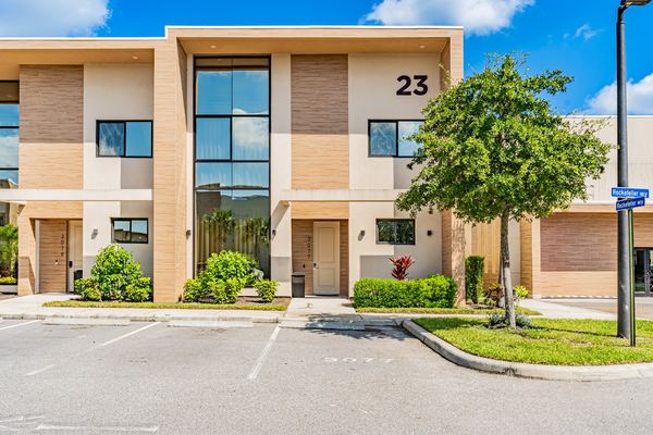 Modern three-story stucco home with a tall glass stair window in Kissimmee