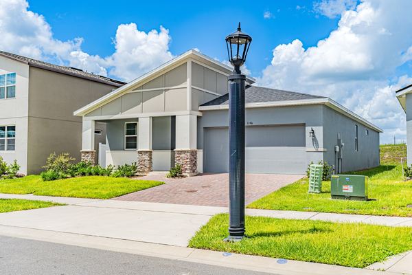 Single-story home with a paver driveway and a black lamppost in Kissimmee