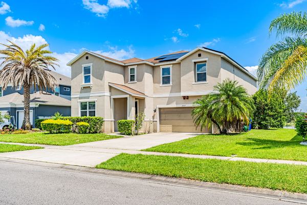 Tan two-story home framed by two palm trees in Kissimmee