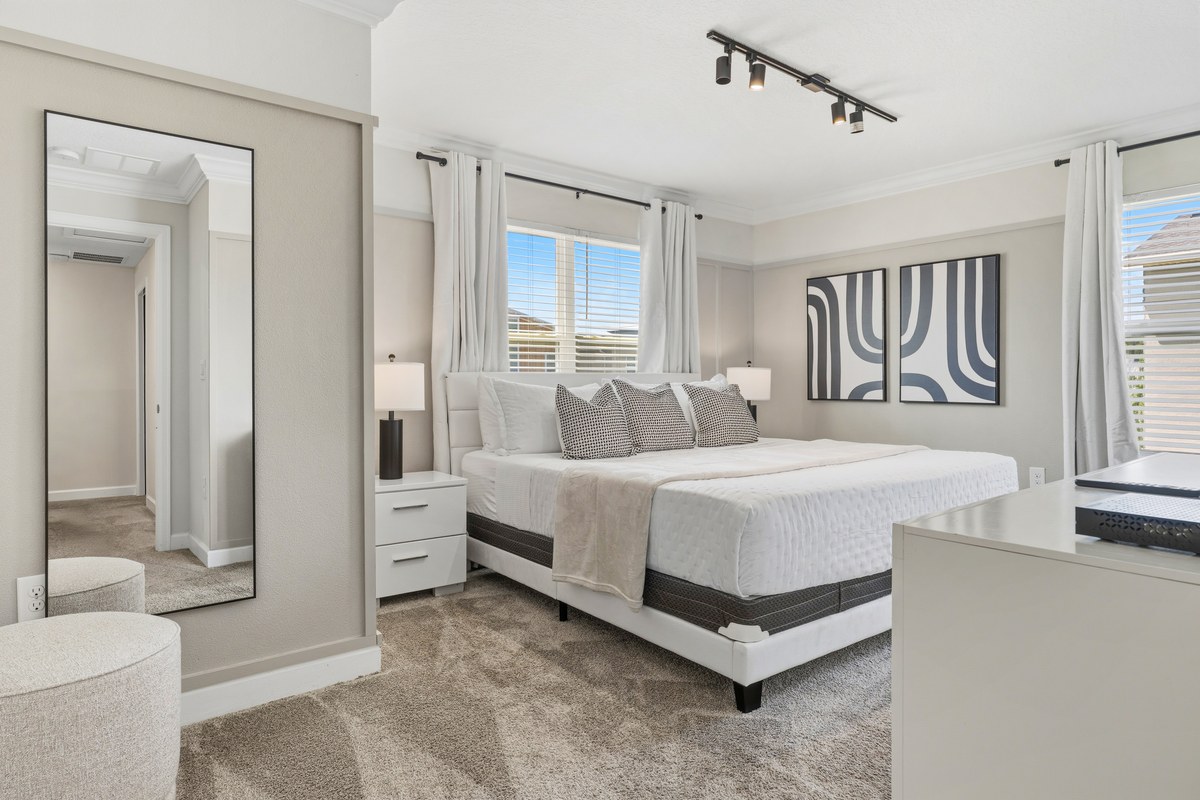 Bedroom with track lighting, a floor mirror and a white bed in Kissimmee