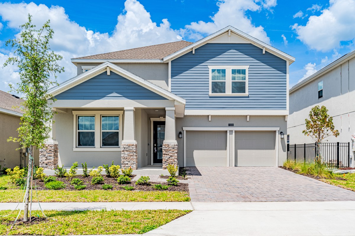 Blue two-story home with two garage bays and a paver driveway in Lake Nona