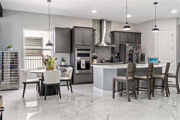 Gray kitchen with a wine refrigerator, dining table and a refrigerator covered in magnets in Lake Nona