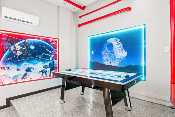 Air hockey table beside backlit space-battle wall murals in Orlando