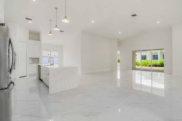 Unfurnished living room with marble floors and the kitchen island beyond in Port Charlotte