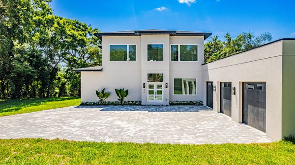 Modern white two-story home with a paver motor court in Windermere