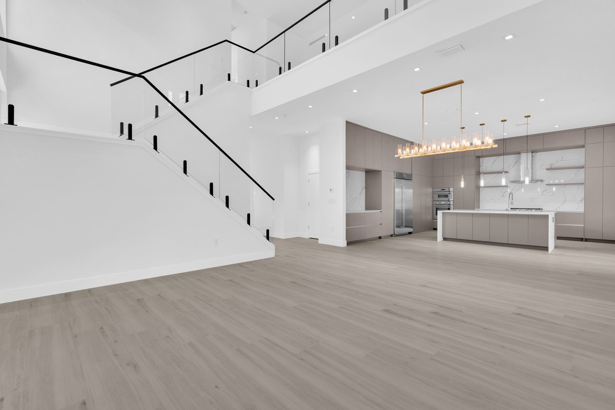 Unfurnished modern living room with a staircase and the kitchen beyond in Windermere