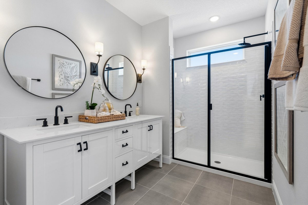 Bathroom with round mirrors, a double vanity and a glass shower in Winter Garden